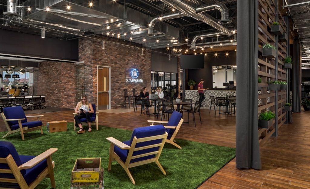 carvana office with exposed industrial ceiling, exposed brick, a green carpet to imitate grass, and hanging wall plants